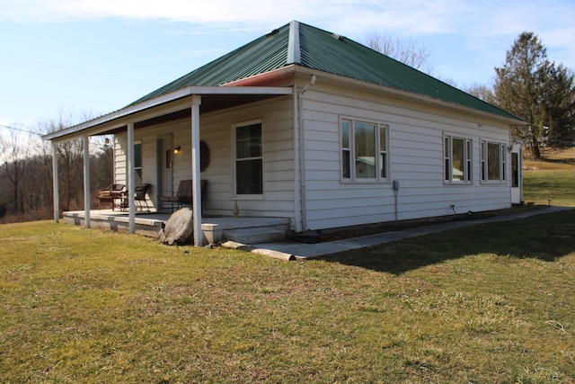 view of property exterior featuring covered porch, metal roof, and a lawn