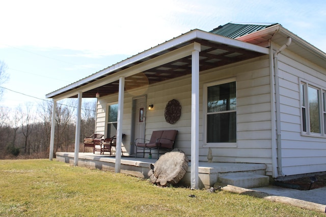 entrance to property featuring metal roof, a yard, and a porch