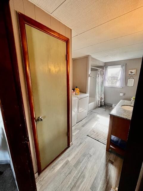 bathroom featuring curtained shower, washer and clothes dryer, wood finished floors, and vanity