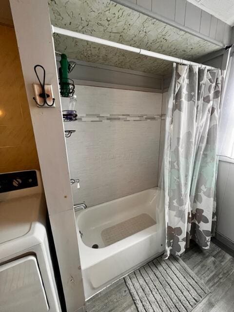 full bathroom featuring washer / dryer, shower / tub combo with curtain, and wood finished floors