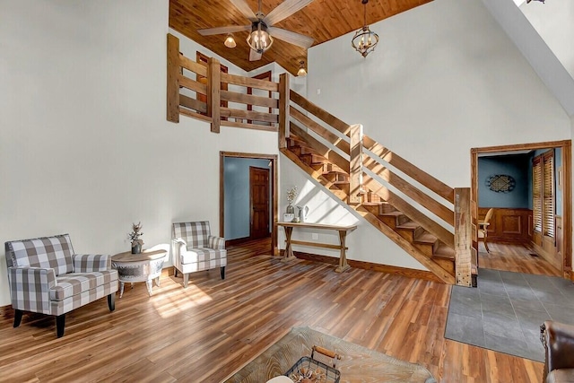 interior space featuring baseboards, wood ceiling, wood finished floors, stairs, and high vaulted ceiling