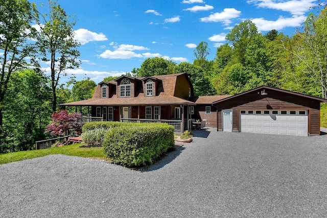 view of front of house featuring driveway, a gambrel roof, roof with shingles, an attached garage, and a porch