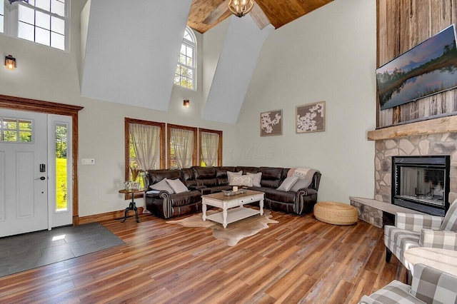 living room featuring baseboards, a fireplace, a high ceiling, and wood finished floors