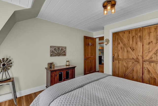 bedroom featuring baseboards, vaulted ceiling, and wood finished floors