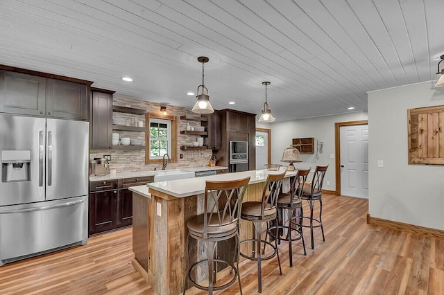 kitchen featuring stainless steel fridge, light countertops, a kitchen bar, open shelves, and a sink