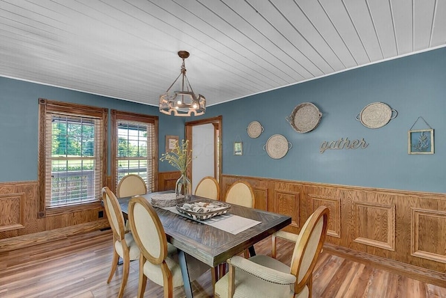 dining space featuring a notable chandelier, light wood-style flooring, wainscoting, wood walls, and wooden ceiling