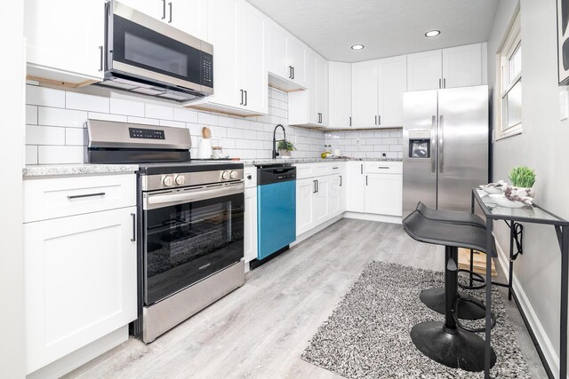 kitchen featuring appliances with stainless steel finishes, white cabinets, and decorative backsplash