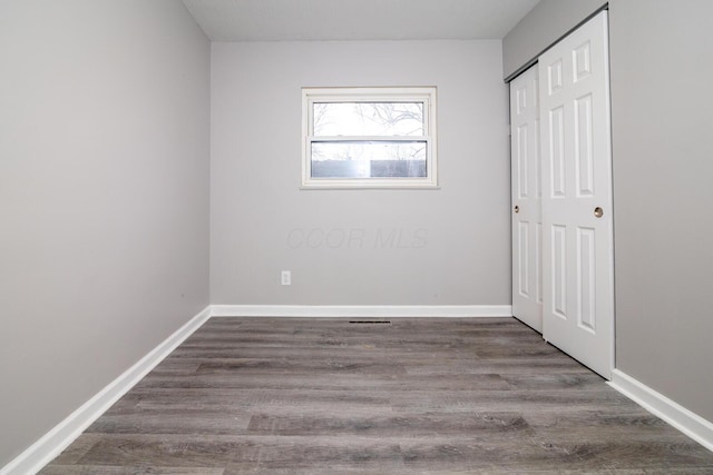 unfurnished bedroom featuring a closet, baseboards, and wood finished floors