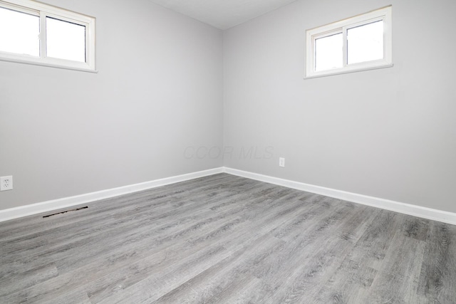 spare room featuring wood finished floors, visible vents, and baseboards