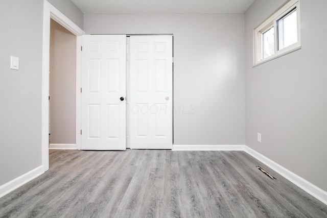 unfurnished bedroom with a closet, wood finished floors, and baseboards