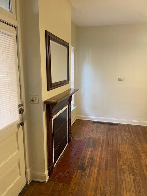 interior space with a fireplace with flush hearth, baseboards, and hardwood / wood-style flooring