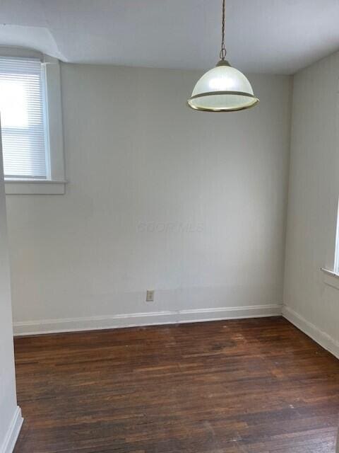 unfurnished room with baseboards and dark wood finished floors