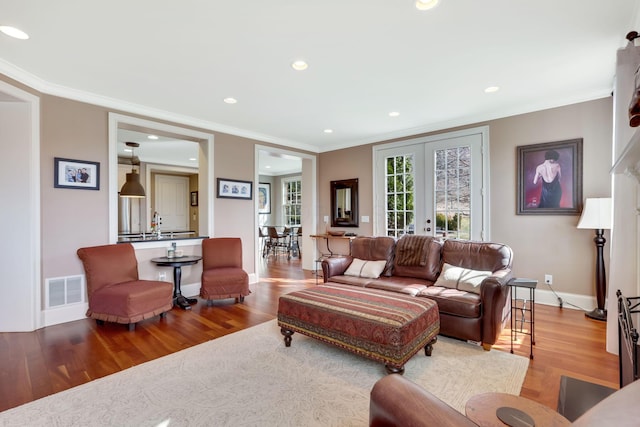 living area featuring ornamental molding, french doors, visible vents, and wood finished floors