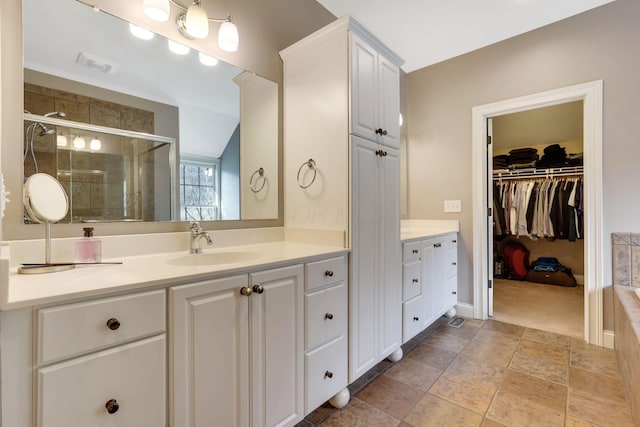 bathroom with visible vents, a spacious closet, a stall shower, vanity, and baseboards