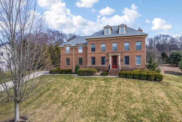 colonial-style house featuring a front yard and brick siding