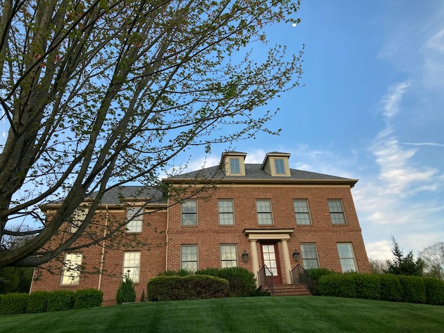 georgian-style home featuring brick siding and a front yard