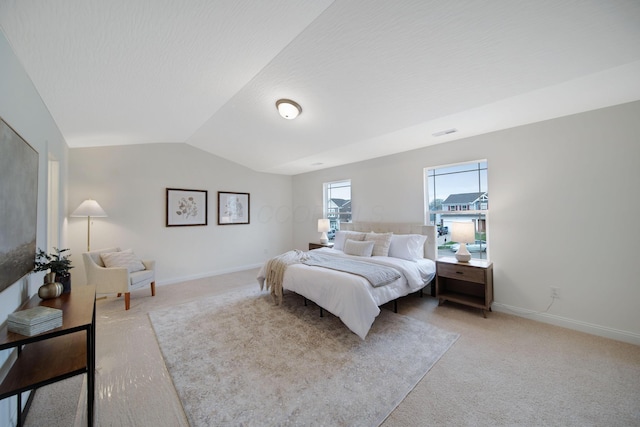 bedroom with light colored carpet, lofted ceiling, baseboards, and visible vents