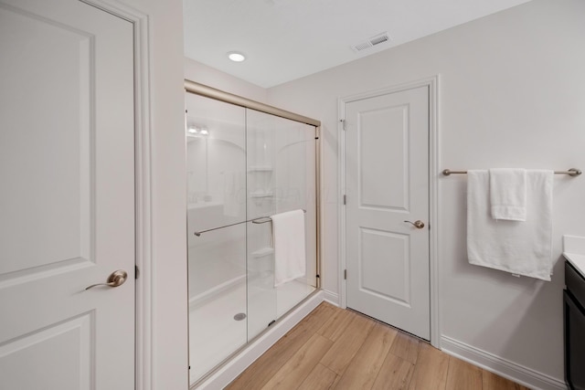 bathroom with visible vents, a shower stall, baseboards, wood finished floors, and vanity