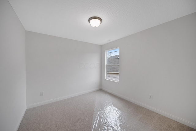 spare room featuring baseboards and light carpet