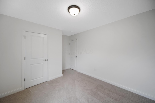 unfurnished bedroom featuring baseboards and light colored carpet