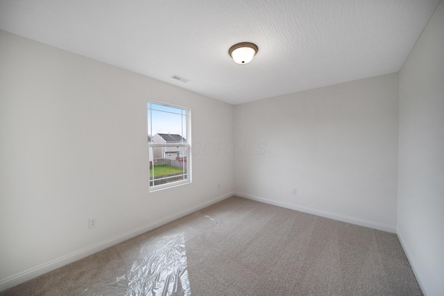 unfurnished room with light carpet, visible vents, and baseboards