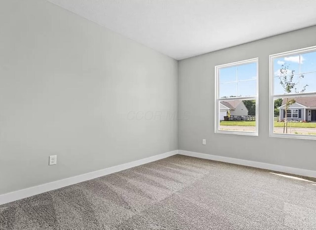 carpeted empty room featuring plenty of natural light and baseboards