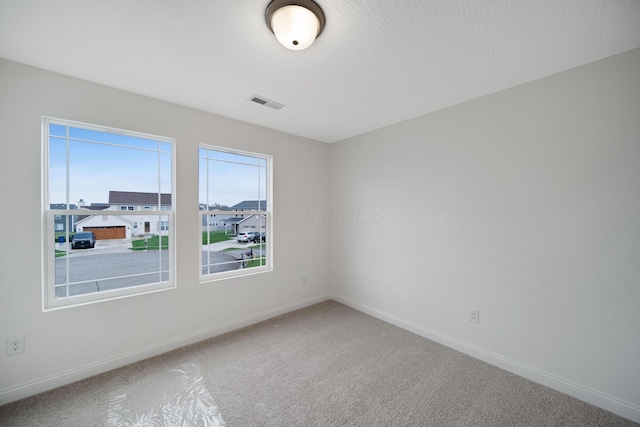 carpeted empty room featuring visible vents and baseboards