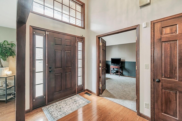 foyer entrance with plenty of natural light, a towering ceiling, and light wood-style floors