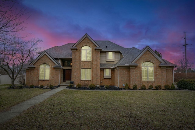 traditional home with brick siding, fence, a front lawn, and roof with shingles