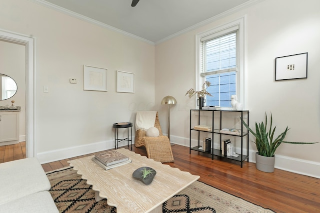 living area with hardwood / wood-style flooring, a ceiling fan, baseboards, and crown molding