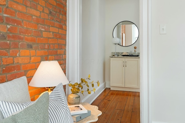 bathroom featuring brick wall, baseboards, vanity, and hardwood / wood-style floors