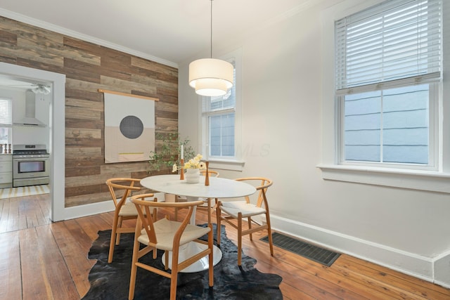 dining area with wood-type flooring, visible vents, and crown molding