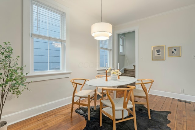 dining area featuring baseboards, crown molding, stairway, and hardwood / wood-style floors