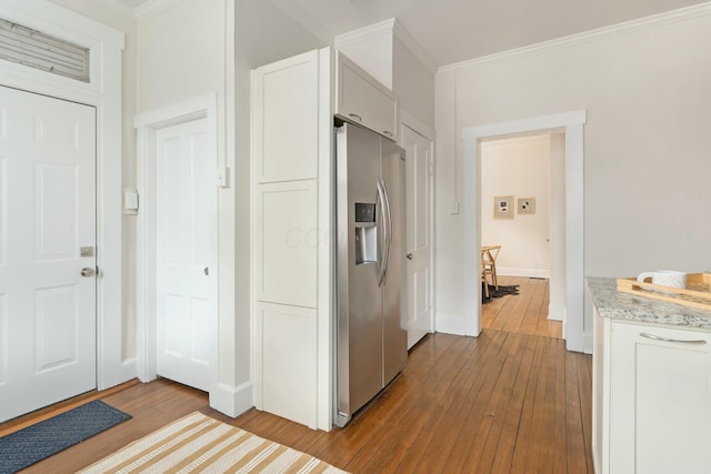 kitchen featuring stainless steel fridge, baseboards, white cabinets, wood-type flooring, and crown molding