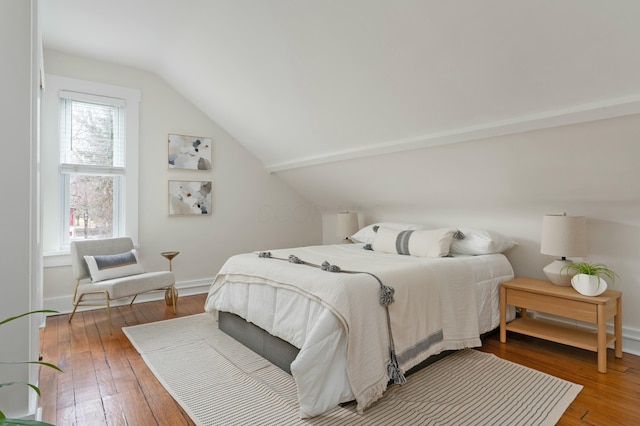 bedroom featuring lofted ceiling, wood-type flooring, and baseboards