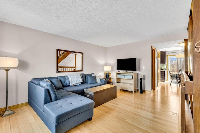 living room with beverage cooler, baseboards, light wood finished floors, and a textured ceiling