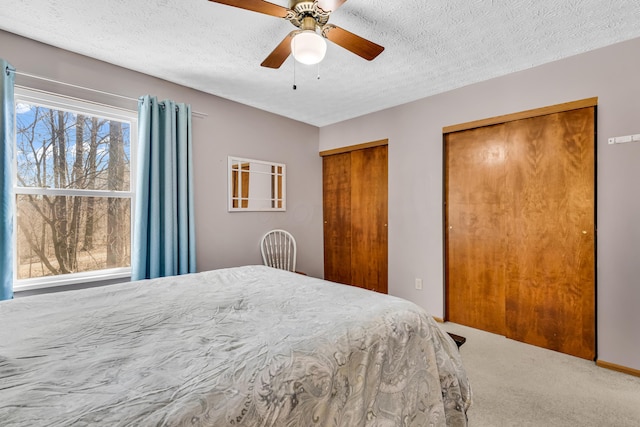 bedroom featuring a textured ceiling, two closets, a ceiling fan, and carpet floors