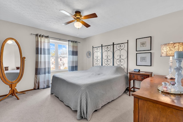 bedroom with a ceiling fan, light colored carpet, baseboards, and a textured ceiling