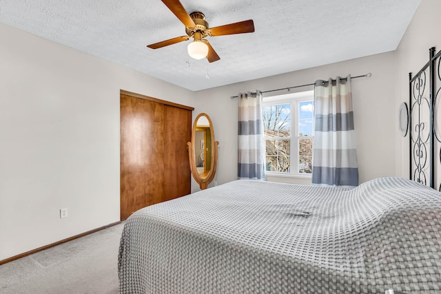 carpeted bedroom featuring a closet, baseboards, a textured ceiling, and ceiling fan