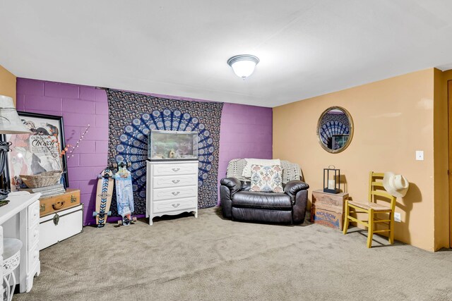 sitting room with concrete block wall and carpet flooring