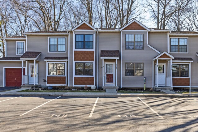 multi unit property with uncovered parking, a shingled roof, and entry steps