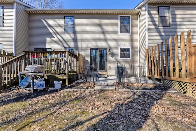 rear view of house featuring central air condition unit, a wooden deck, and fence