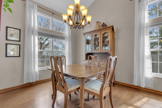 dining room with baseboards, light wood finished floors, and an inviting chandelier