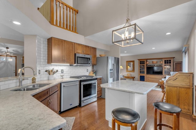 kitchen featuring stainless steel appliances, light wood finished floors, a sink, and brown cabinets