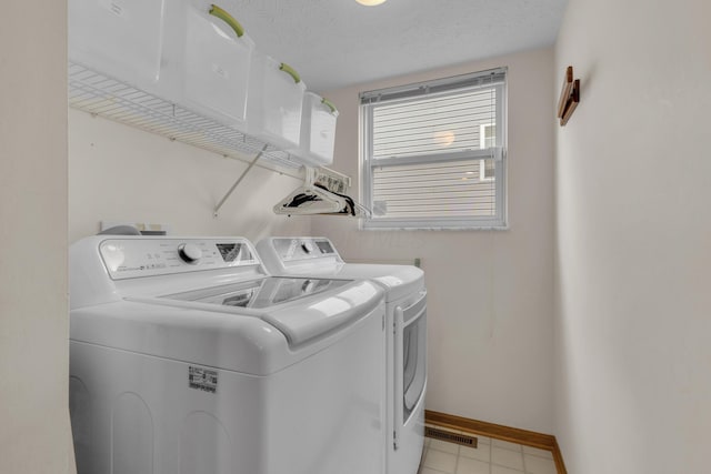 laundry room with laundry area, washing machine and dryer, baseboards, and a textured ceiling