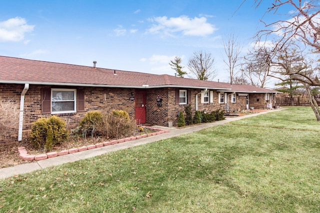 ranch-style home with roof with shingles, a front yard, and brick siding