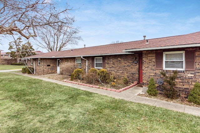 ranch-style home with brick siding, a front lawn, and a shingled roof