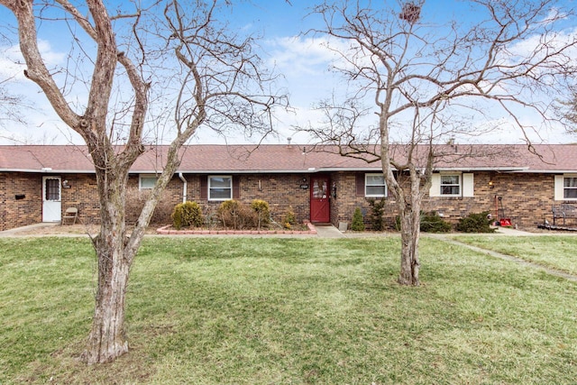 ranch-style home featuring brick siding, roof with shingles, and a front yard