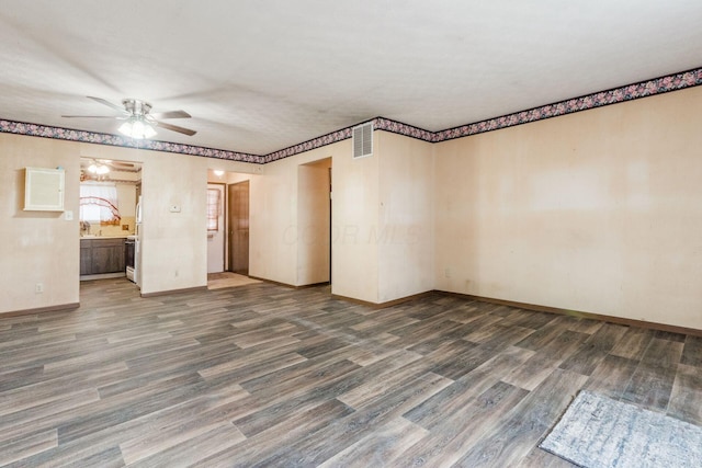 spare room featuring a ceiling fan, visible vents, baseboards, and wood finished floors