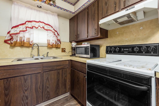 kitchen with under cabinet range hood, a sink, light countertops, electric range oven, and stainless steel microwave